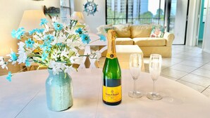 A table with a bottle of Veuve Clicquot Brut champagne, two glasses, and a vase of flowers.