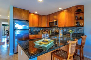 A modern kitchen with wooden cabinets, stainless steel appliances, and a granite countertop.
