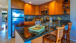 Una cocina moderna con armarios de madera, electrodomésticos de acero inoxidable y encimera de granito.