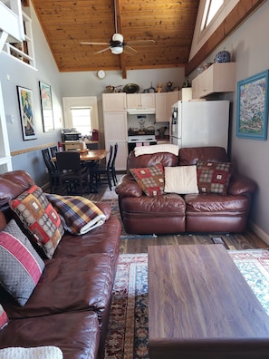 A cozy living room with a brown leather couch, a wooden coffee table, and a patterned rug.