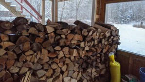 A room with a large stack of firewood against a window, a wooden staircase, and a yellow container. - Hike, ski, summer fun in our all season home minutes to Okemo. Dogs welcome! (Mt Holly)
