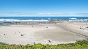 Ein Strand mit Menschen, Zelten und einer felsigen Küstenlinie.