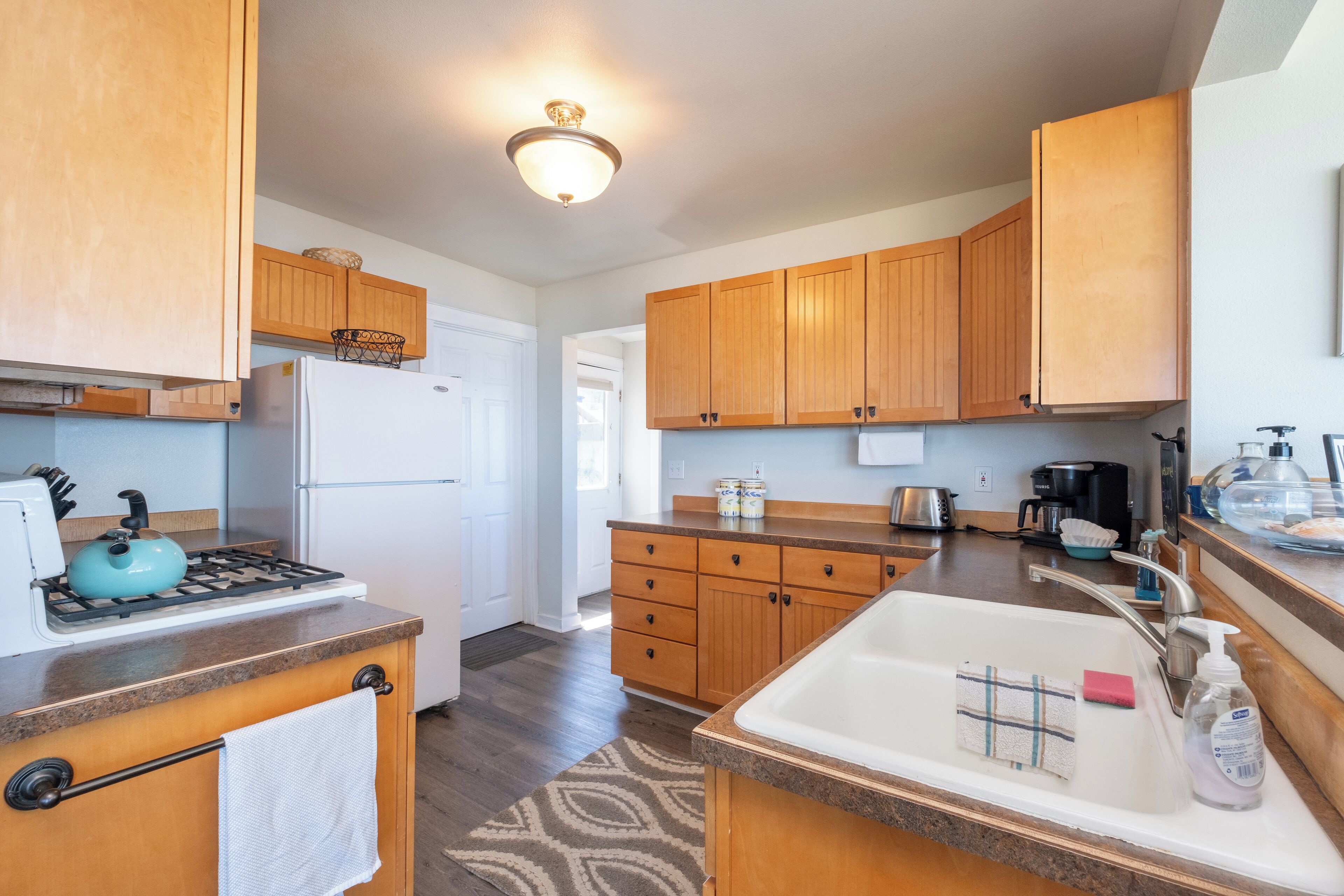 A kitchen with wooden cabinets, a stove, a sink, and a countertop.
