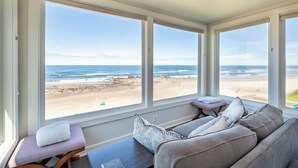 Ein Zimmer mit großem Fenster und Meerblick, einer Couch und einem kleinen Tisch.