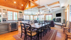 A spacious kitchen with wooden beams, a large dining table, and a fireplace. - 43 Dune Lane - 2nd Row Dune Lane Luxury, 100ft from the Sand (Hilton Head Island)