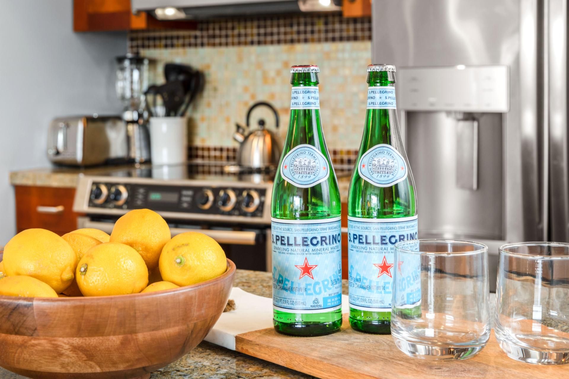 Zwei Flaschen Pellegrino Mineralwasser und eine Schale Zitronen auf einer Küchenarbeitsplatte.