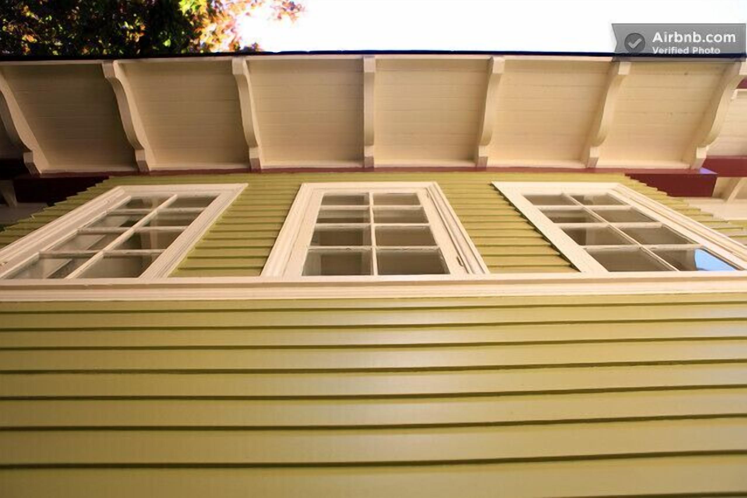 A model of a house with a green exterior, two windows, and a roof with dormer windows.