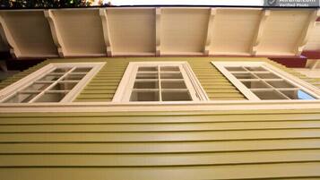 A model of a house with a green exterior, two windows, and a roof with dormer windows.