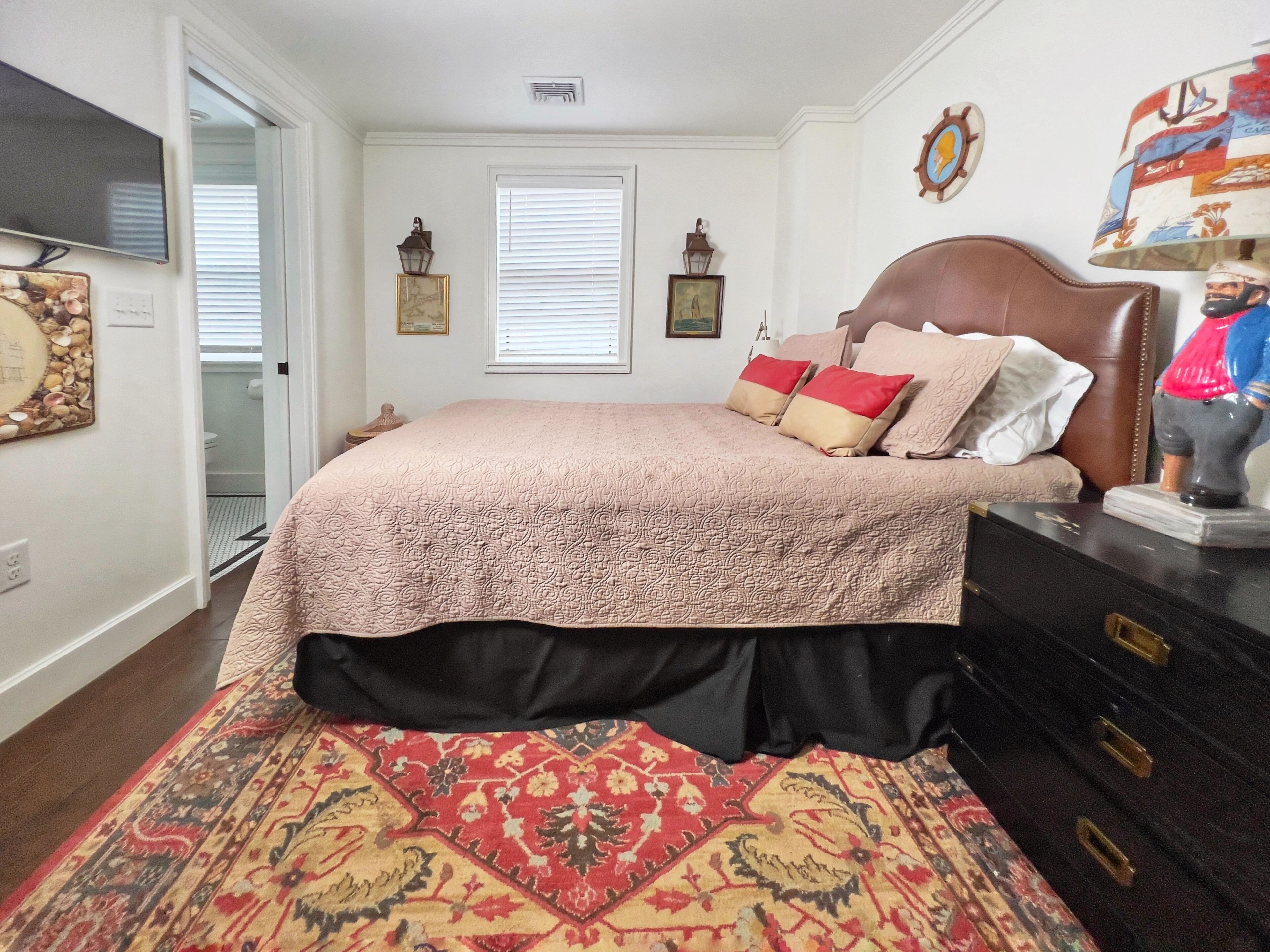 A bedroom with a bed, a dresser, a rug, and a wall clock.