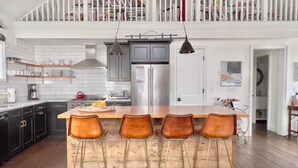 Una cocina amplia con una isla grande, taburetes de bar y un comedor.