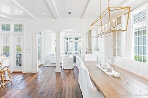 A spacious room with a wooden floor, white furniture, and a large window with a view. - Beachfront with Pool and Golf Cart (Watersound)
