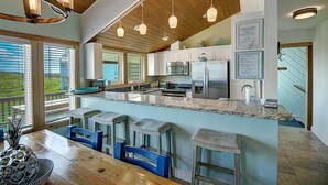 Una cucina moderna con un'ampia isola, elettrodomestici in acciaio inossidabile e soffitto in legno.