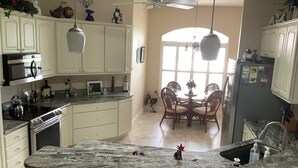 Une cuisine avec des meubles blancs, un plan de travail en marbre et un coin repas comprenant une table et des chaises.