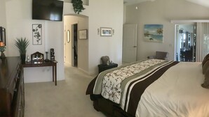 Une chambre à coucher avec un grand lit, des lampes de chevet, une commode et un téléviseur fixé au mur.