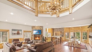 A spacious living room with a fireplace, comfortable seating, a television, and a stone wall.