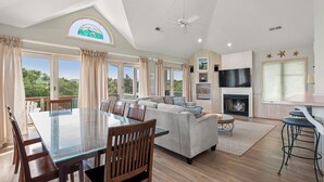 A spacious living area with a glass dining table, a sofa, and a fireplace. - Pelican Shores: Private pool, 4 bedrooms, Whalehead Beach (Corolla)