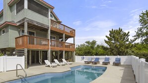 A two-story house with a balcony, a swimming pool, and several lounge chairs. - Pelican Shores: Private pool, 4 bedrooms, Whalehead Beach (Corolla)