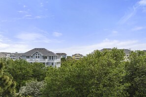 Un quartier résidentiel composé de plusieurs maisons, entouré d’une végétation luxuriante et surplombé d’un ciel bleu azur.