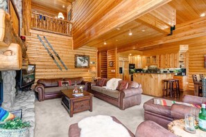 L’intérieur d’une cabane en rondins comprend un salon, une cuisine et un escalier menant à une mezzanine.