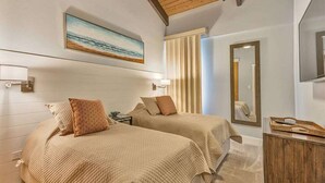 Una camera da letto con due letti, una ventola a soffitto, un quadro, uno specchio e un comò in legno.
