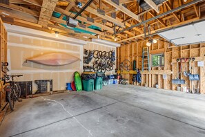 Un garage spacieux doté d’un sol en béton, de poutres en bois et d’un support à vélos fixé au mur.
