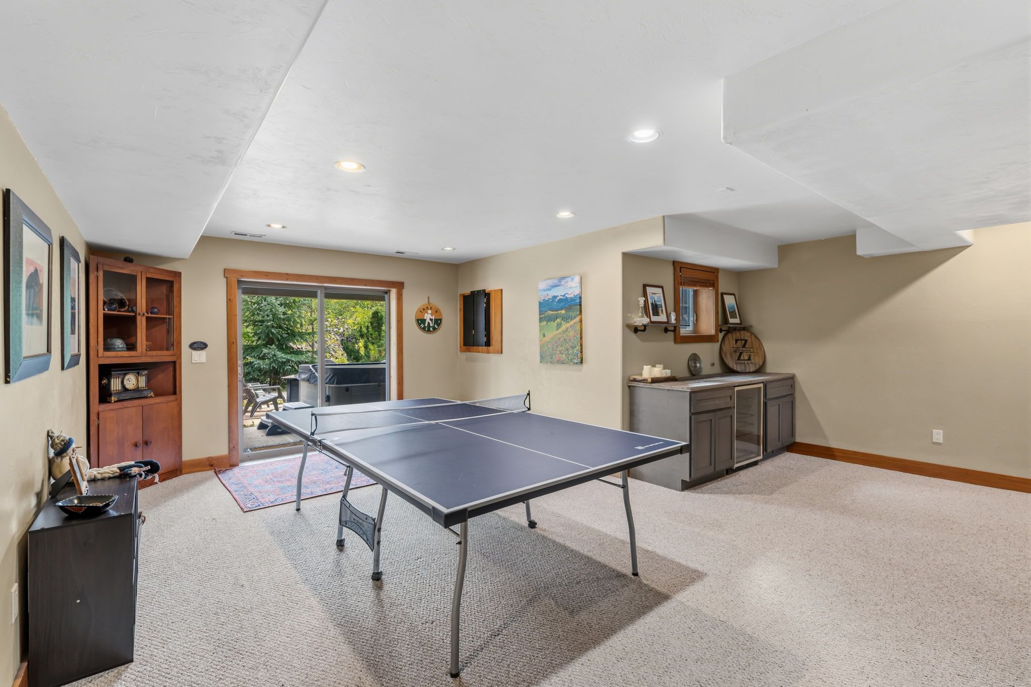 A spacious room with a ping pong table, a wooden cabinet, and a large window.