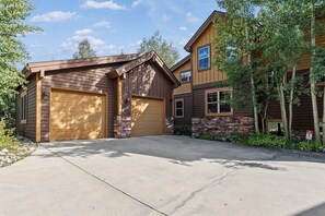 Une maison à deux étages avec un garage, des fondations en pierre et une allée.