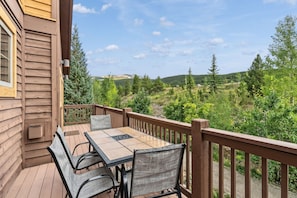 Eine Holzterrasse mit Tisch und Stühlen mit Blick auf eine bewaldete Landschaft.