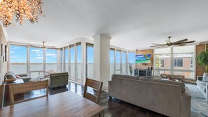 Ein geräumiger Wohnbereich mit Esstisch, Sofas und einem großen Fenster mit Blick aufs Wasser.