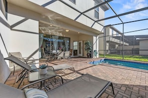 A covered outdoor area with a pool, seating, and a view of the surrounding landscape. - Lake Access: 5BR Pool Townhouse near WDW (Kissimmee)
