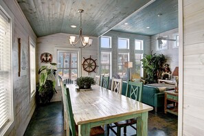 Comedor con temática náutica, que incluye una mesa de madera, sillas y un adorno con timón de barco.