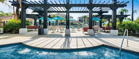 A pool area with a pergola, lounge chairs, and umbrellas.