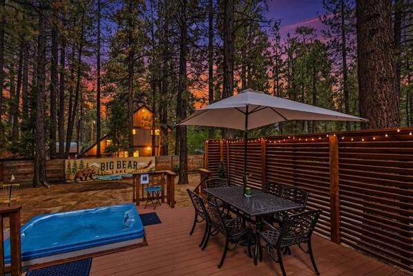Una terraza con piscina, mobiliario exterior y vistas a una cabaña identificada como 'Big Bear Lake'.