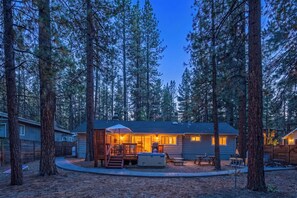 Une cabane dotée d’une terrasse, entourée de grands pins.
