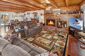 A cozy living room with a fireplace, leather sofa, and a patterned rug. - Outdoor Living by Snow Summit! Big Bear Mural! PET FRIENDLY! HOT TUB! Fire Pit! Large Fenced Yard! (Big Bear Lake)