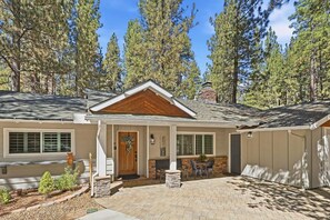 A two-story house with a front porch, a chimney, and a brick driveway. - Outdoor Living by Snow Summit! Big Bear Mural! PET FRIENDLY! HOT TUB! Fire Pit! Large Fenced Yard! (Big Bear Lake)