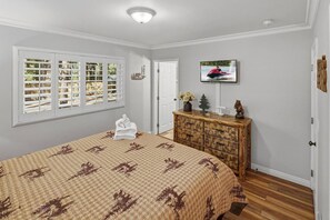 A bedroom with a large bed, a dresser, a television, and a window with blinds. - Outdoor Living by Snow Summit! Big Bear Mural! PET FRIENDLY! HOT TUB! Fire Pit! Large Fenced Yard! (Big Bear Lake)