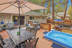 Un jardin avec un jacuzzi, du mobilier d’extérieur, un barbecue et une terrasse en bois.