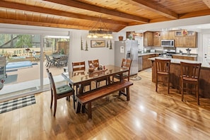 Una cocina amplia con gabinetes de madera, un comedor con una mesa grande y bancos, y vistas al Lago Big Bear.