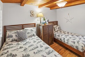 A bedroom with two beds, a nightstand, a lamp, and a star decoration on the wall. - Outdoor Living by Snow Summit! Big Bear Mural! PET FRIENDLY! HOT TUB! Fire Pit! Large Fenced Yard! (Big Bear Lake)