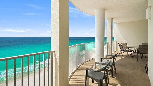 A balcony with a view of the ocean, a table with chairs, and a white railing. - CONDO WITH AMAZING VIEWS & SPACIOUS BALCONY!! SLEEPS UP TO 8! (Panama City Beach)