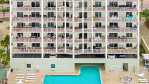 A multi-story hotel with balconies, a swimming pool, and outdoor seating. - CONDO WITH AMAZING VIEWS & SPACIOUS BALCONY!! SLEEPS UP TO 8! (Panama City Beach)