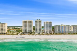 Un hotel costero con varios edificios altos, una playa y cielos despejados.
