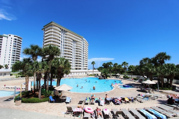 Un resort con una piscina grande rodeada de palmeras y tumbonas.