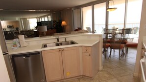 A modern kitchen with a dishwasher, a sink, and a dining area with chairs and a table.