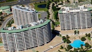 A high-rise hotel with multiple floors, a swimming pool, and a landscaped area.