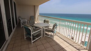 A balcony with a view of the ocean, furnished with chairs and a table.