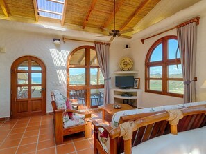 Relax in this spacious room with a high ceiling, arched windows, and a comfortable seating area featuring a sofa and chair.