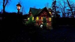 Une cabane en rondins avec une véranda et un lampadaire.