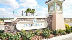 A sign for 'The Retreat' with a stone wall and a small tower-like structure. - Stunning Town Home with Splash Pool in Champions Gate Resort - Close to Theme Parks (Davenport)